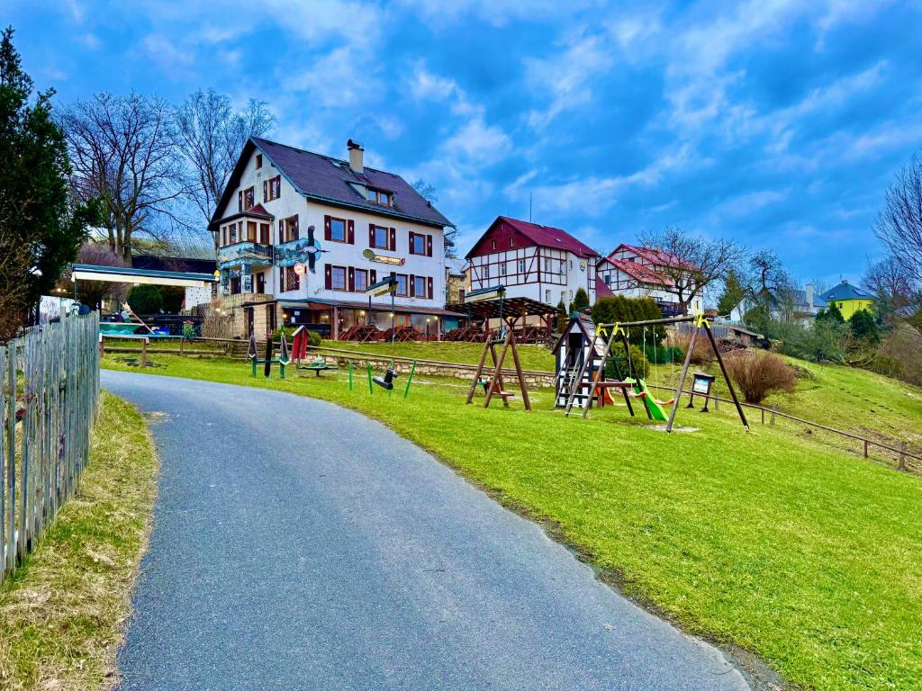 una casa al lado de una carretera con un parque infantil en Resort Mezná, en Hřensko