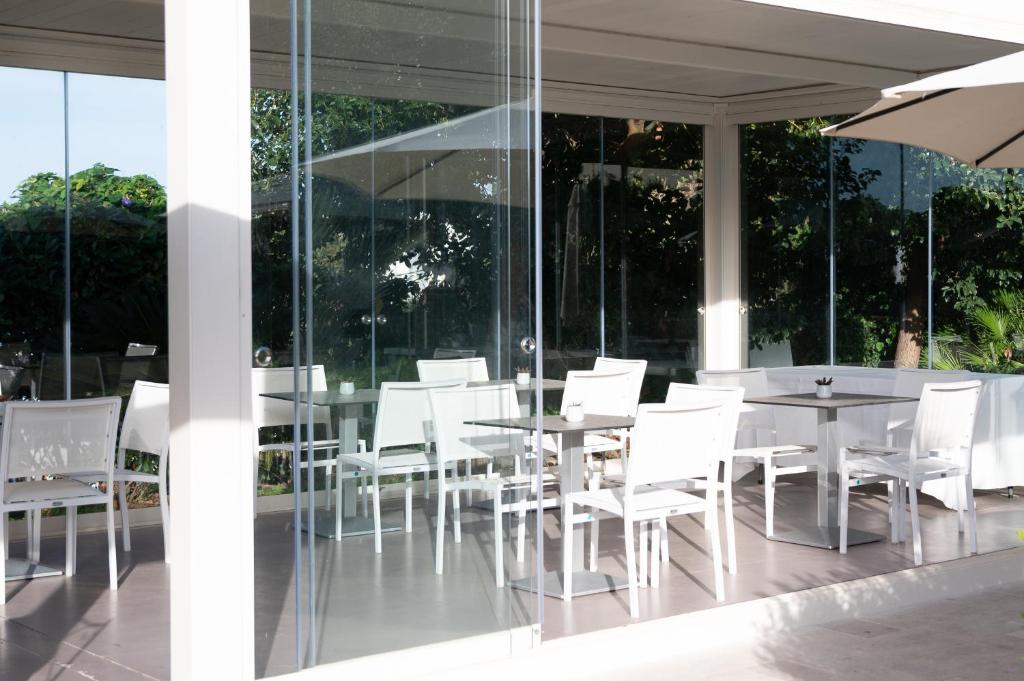 a restaurant with white chairs and tables and windows at Il Leone Di Mare in Procida