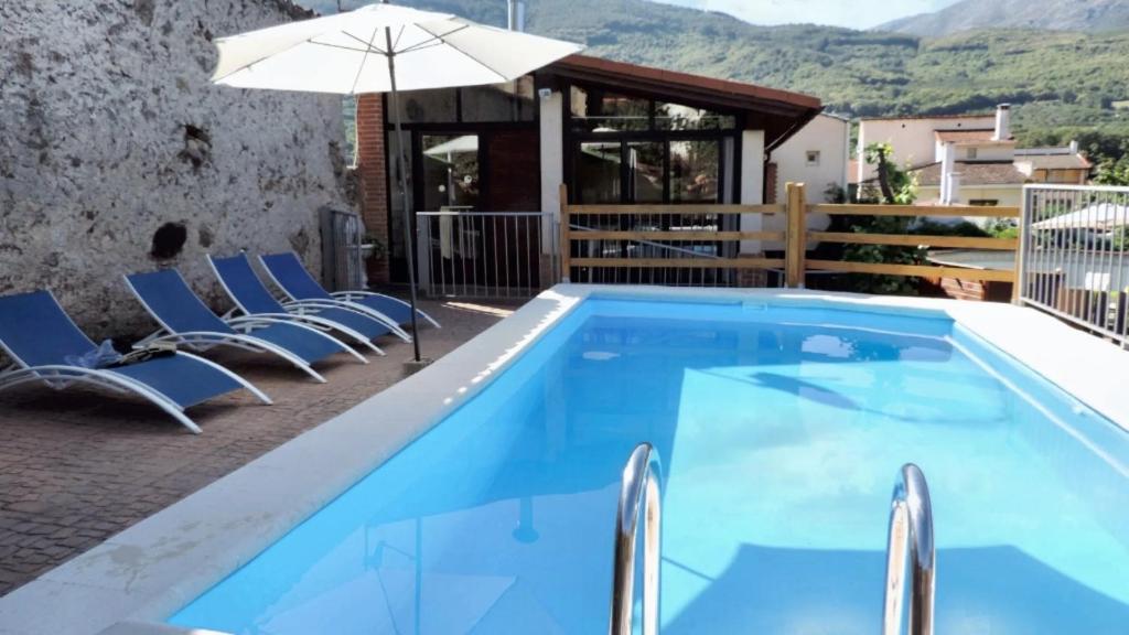a swimming pool with chairs and an umbrella at 5 bedrooms villa with private pool enclosed garden and wifi at Jerte in Jerte