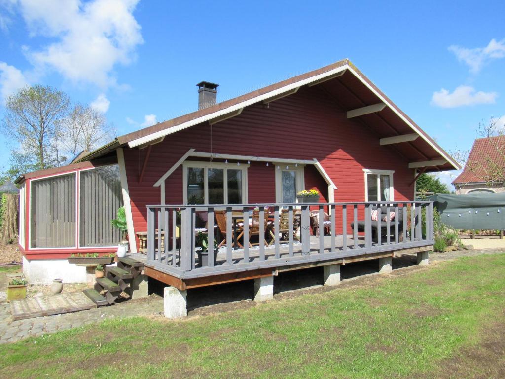 een rood huis met een veranda en een balkon bij Gilou in Koekelare