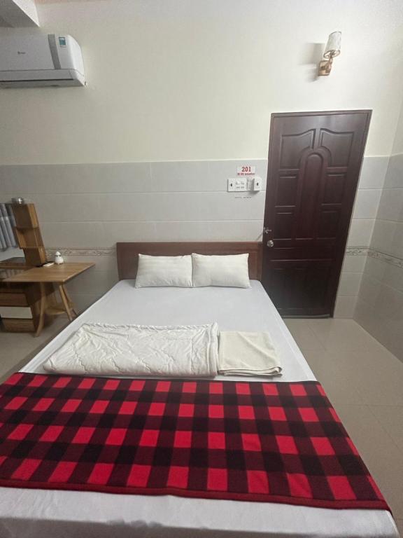 Bett in einem Zimmer mit einem karierten Teppich auf dem Boden in der Unterkunft HOTEL ANH TUẤN in Ấp Cái Giá