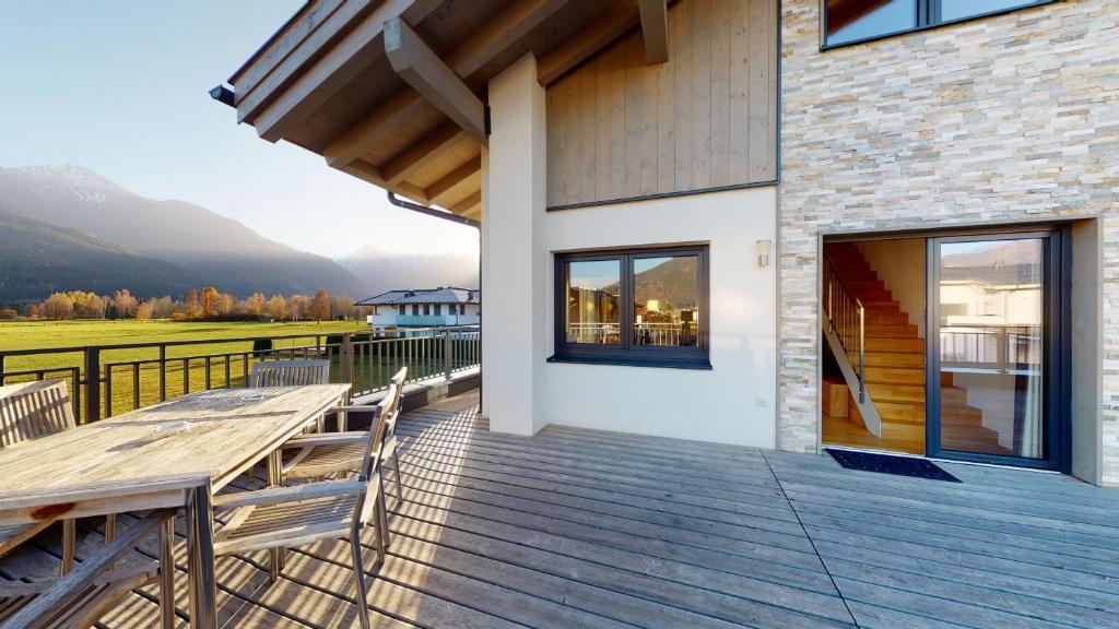 um deque de madeira com uma mesa e cadeiras numa casa em Apart-Chalet Kitzblick em Zell am See