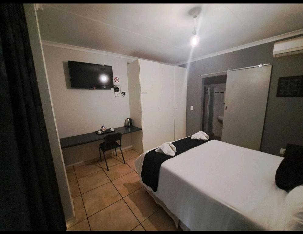 een hotelkamer met een bed en een bureau bij Nikita Portuguese Restaurant and Motel in Lanseria