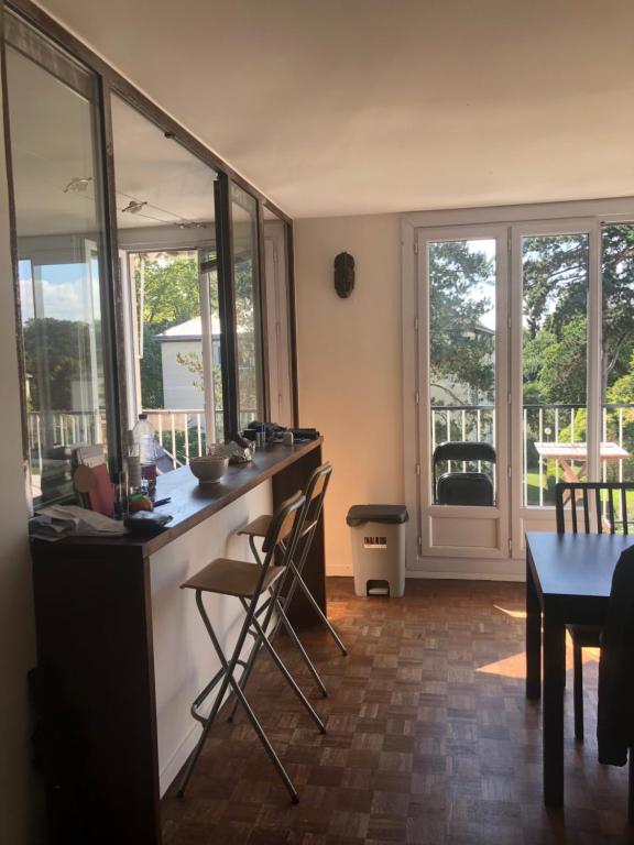 une cuisine avec un comptoir, des chaises et une table dans l'établissement Appartement idéal JO, à Maisons-Laffitte