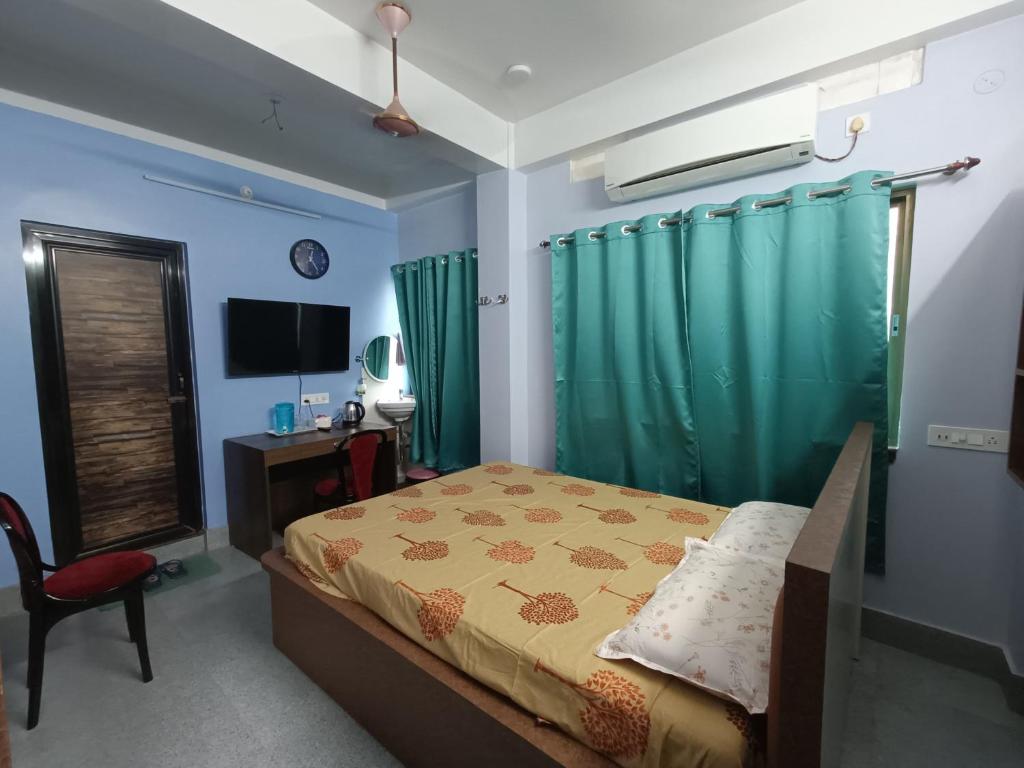 a bedroom with a bed and a desk and a television at Ujjayanta Homestay in Agartala