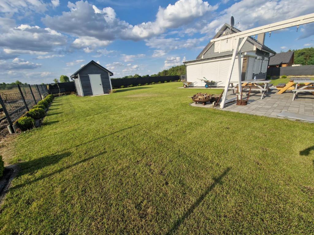 duży dziedziniec z białą stodołą i zieloną trawą w obiekcie Domek Skandynawski w mieście Przykona