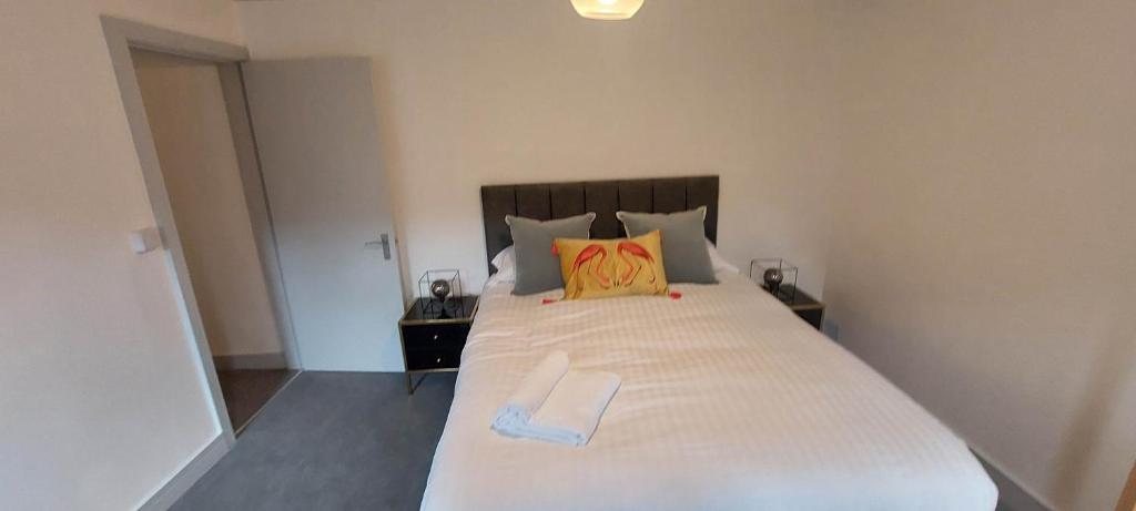 1 dormitorio con 1 cama blanca grande con almohada amarilla en 2 Bedroom Modern Living in The Old Bank House in Market Rasen en Market Rasen