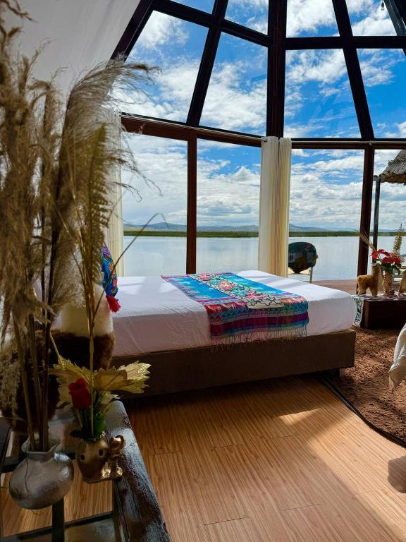 a bedroom with a bed in front of a large window at WIÑAY TITICACA LODGE in Puno