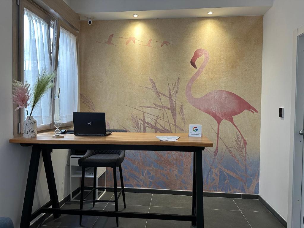 Zimmer mit einem Schreibtisch und einem Flamingo-Gemälde an der Wand in der Unterkunft NG Guest House il Gallura in Olbia