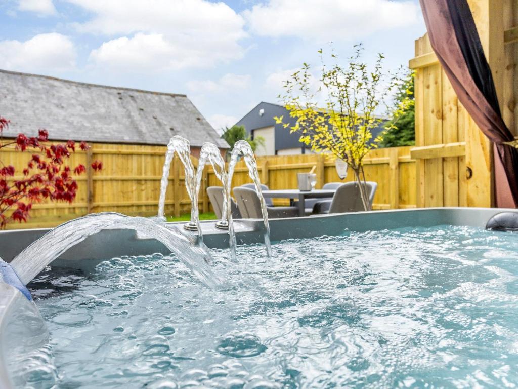 una bañera de hidromasaje con chorros de agua en un patio trasero en City to Country Retreat Luxury Cottage with Hot Tub, en Toppesfield