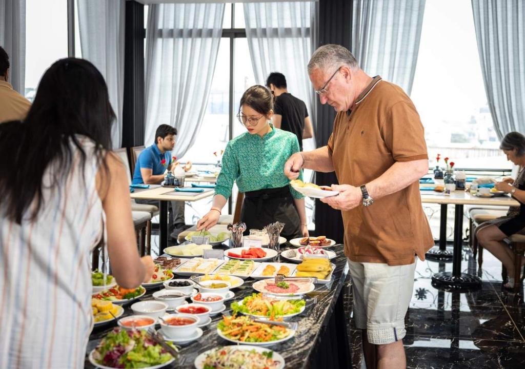 a group of people standing around a buffet of food at Hanoi Old Quarter Hotel in Hanoi