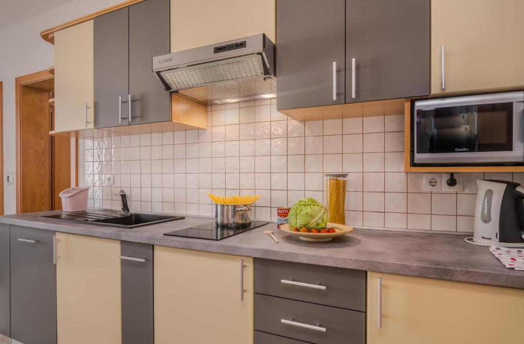 eine Küche mit Spüle und eine Schale mit Gemüse auf der Theke in der Unterkunft Apartments Kvarner in Malinska