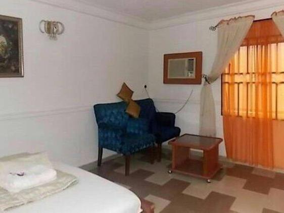 a living room with a blue chair and a table at Precious Palm Royal Hotel in Benin City