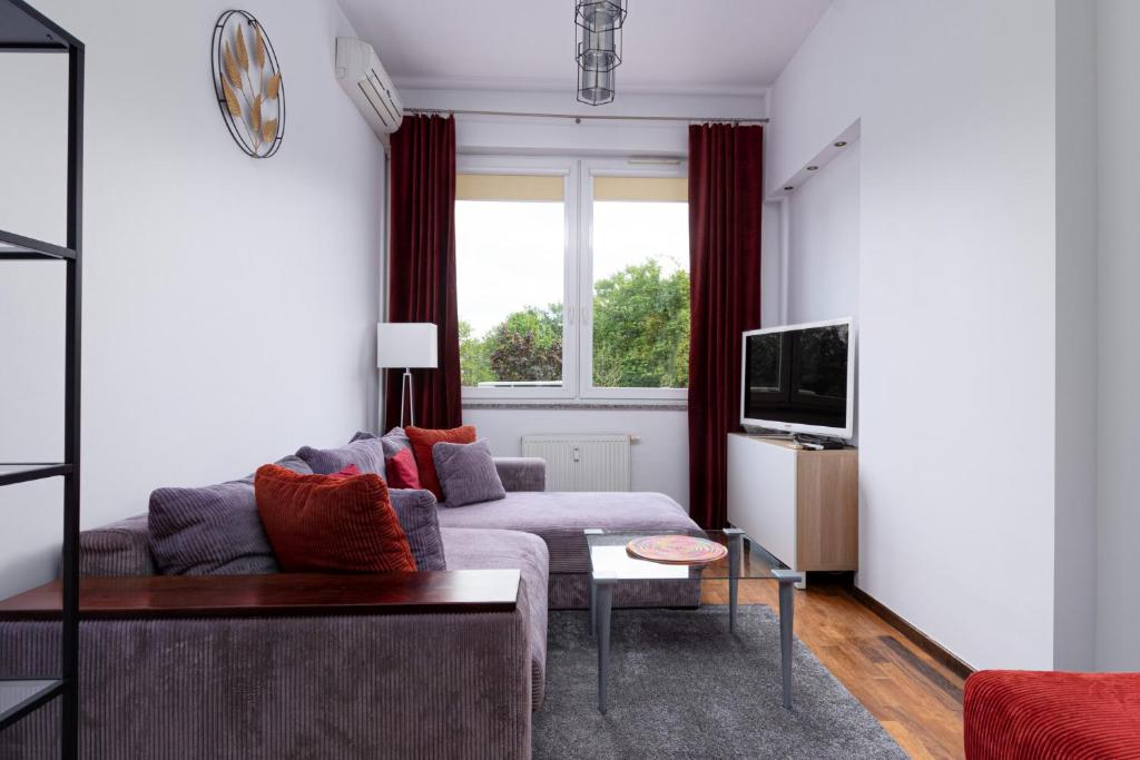 een woonkamer met een bank en een tv bij Powstańców Śląskich Homely Apartment in Wrocław