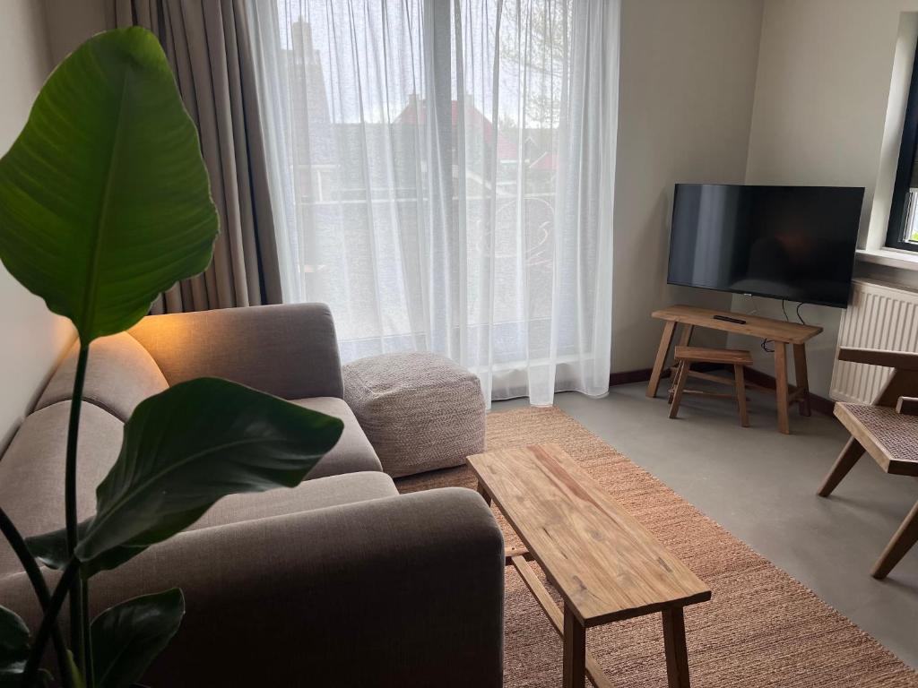 a living room with a couch and a tv at Van Heeckeren City Centre Studios Nes in Nes