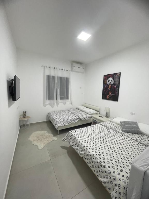 two beds in a room with white walls at וילת צאלים in Yeroẖam