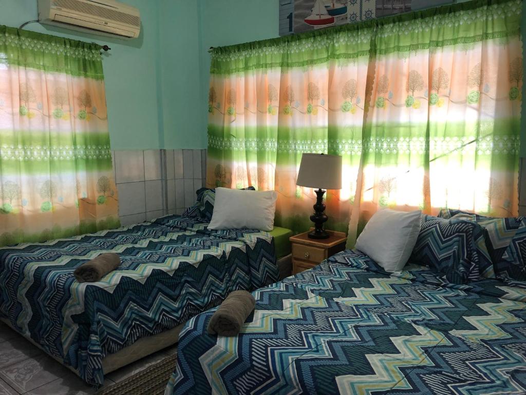 a bedroom with two beds and a lamp and curtains at Caribbean Tourist Villa in Port-of-Spain