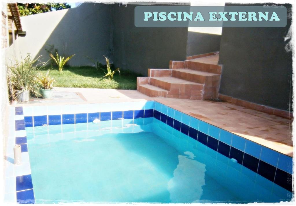 een zwembad met blauwe tegels aan de zijkant van een huis bij HoStel de Setiba - HOSPEDARIA OCA RUCA in Guarapari