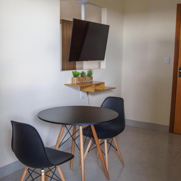 uma mesa com quatro cadeiras e uma televisão na parede em De Paula Apart Hotel em Espigão dʼOeste