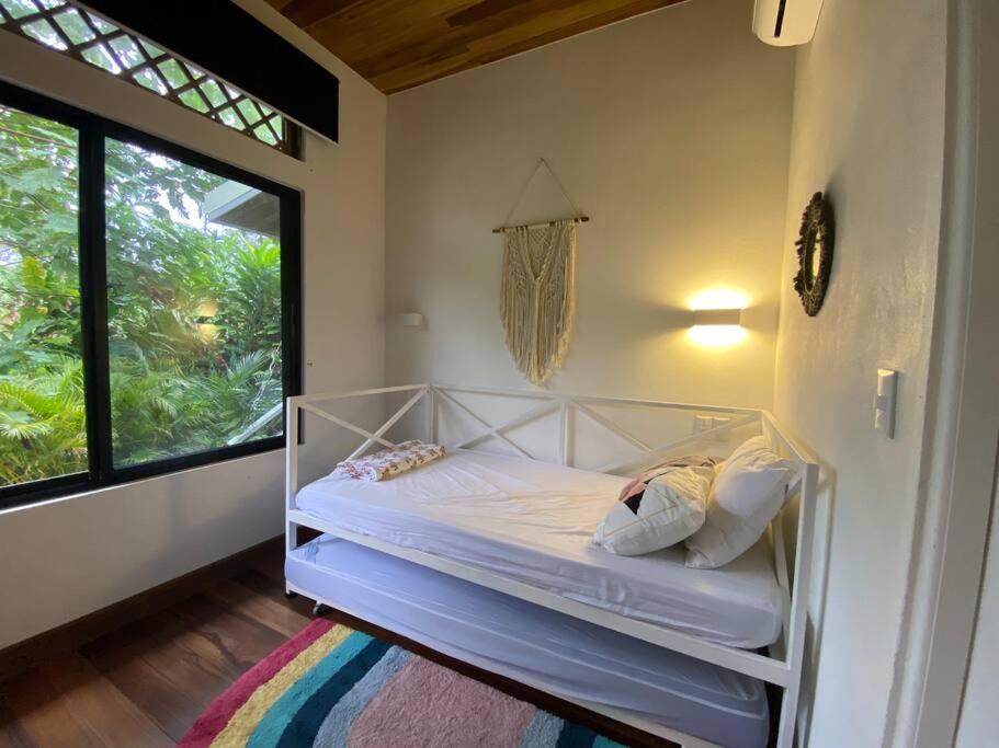 Bett in einem Zimmer mit einem großen Fenster in der Unterkunft Jungle Bungalow with Small Pool in Talamanca