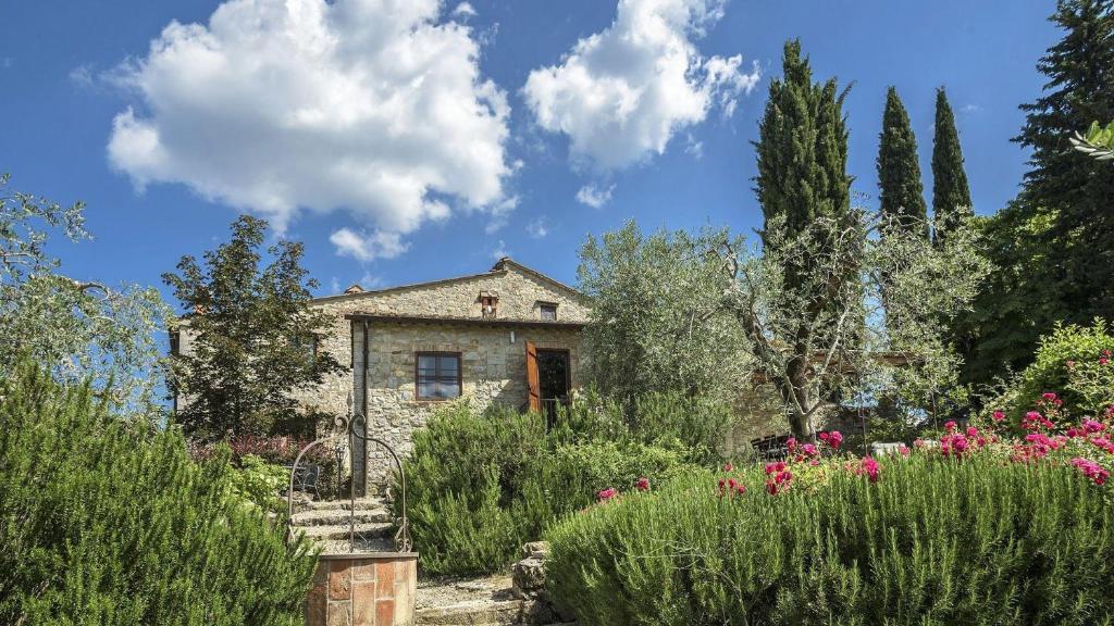 ein Steinhaus in einem Garten mit Blumen in der Unterkunft L'Oliveta in Gaiole in Chianti