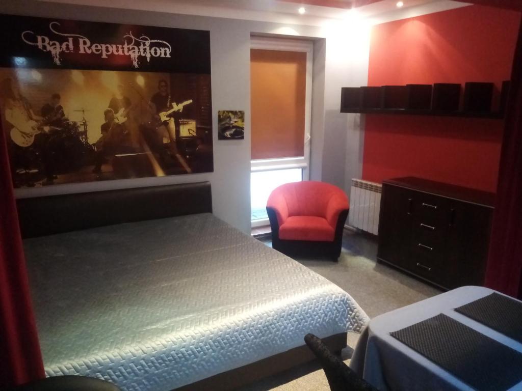 een slaapkamer met een bed en een rode stoel bij Apartament Rosso in Kielce