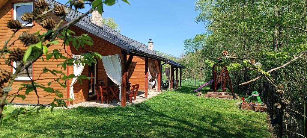 ein Blockhaus mit einem Hof neben einem Haus in der Unterkunft Domki Nad Potokiem in Tyrawa Wołoska