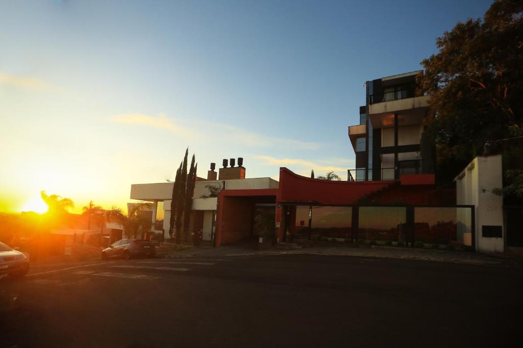 a building with the sun setting in the background at Pousada Sol Pato Branco in Pato Branco
