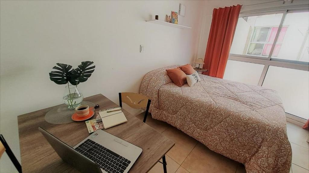a bedroom with a bed and a desk with a laptop at Hornera Balcarce - Depto estudio Cerca de todo in Rosario