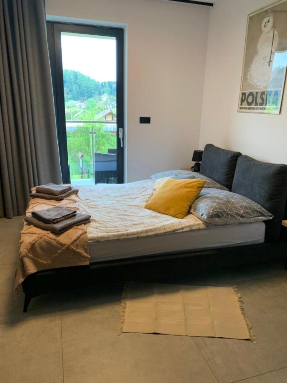 a bed with yellow pillows in a room with a window at Apartament w Dolinie Sanu 1 in Lesko