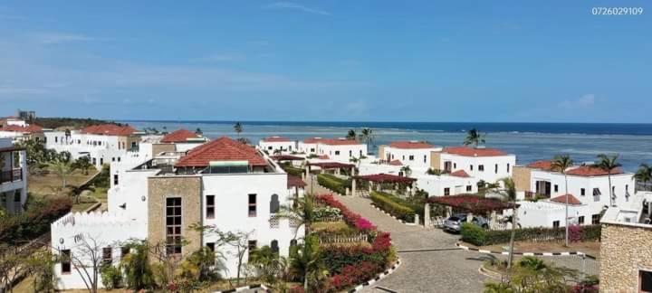 Sultan Palace Beach Home- Ahsan في مومباسا: مجموعة من المنازل البيضاء مع المحيط في الخلفية