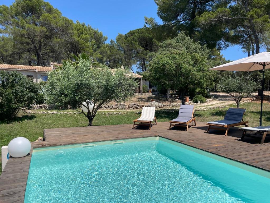 een zwembad met 2 stoelen en een parasol bij Villa au calme dans un domaine boisé in La Motte