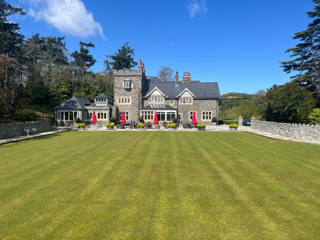 a large grass field in front of a large house at The Manor Boutique Hotel Restaurant and Bar in Conwy