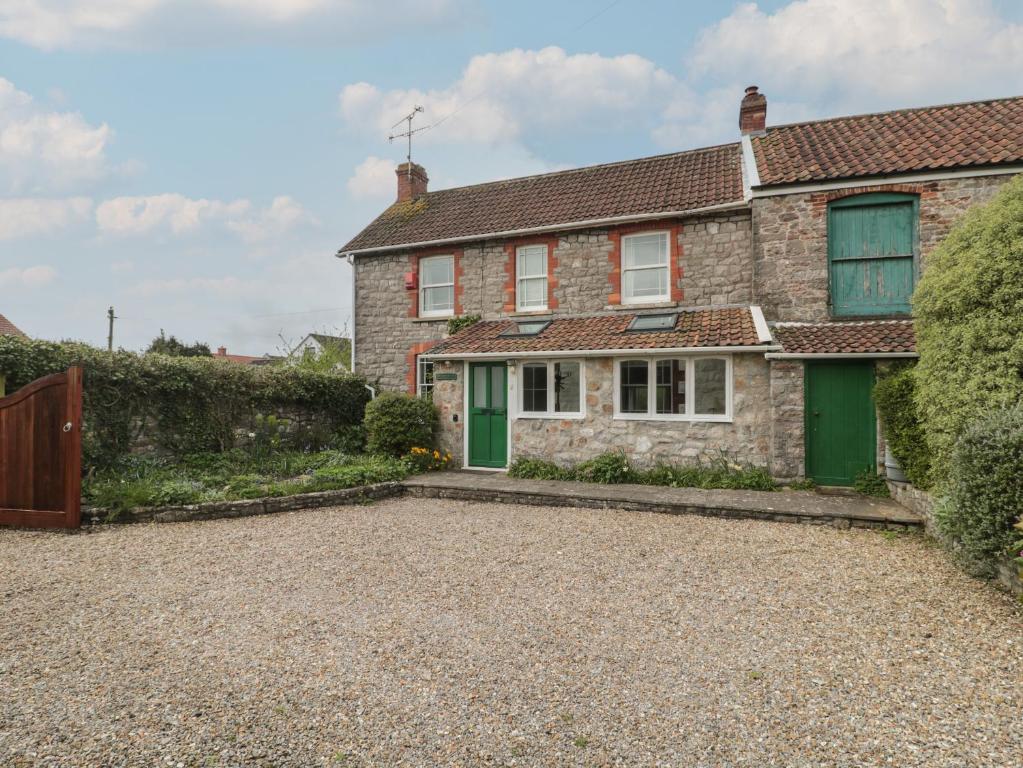 a brick house with green doors and a gravel driveway at Cathay House in Cheddar