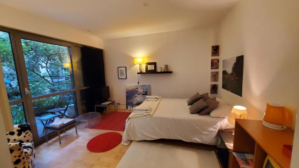- une chambre avec un lit et une grande fenêtre dans l'établissement Une chambre à Paris 20eme avec un petit jardin, à Paris