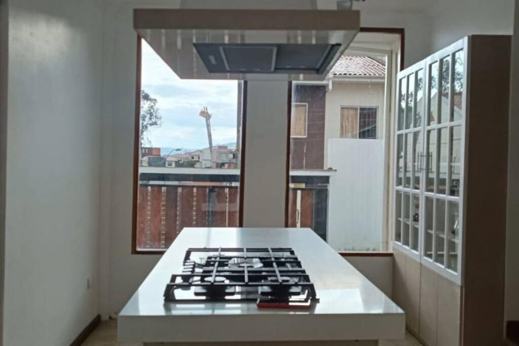 a kitchen with a stove and a large window at Vive con nosotros tusvacaciones in Cuenca