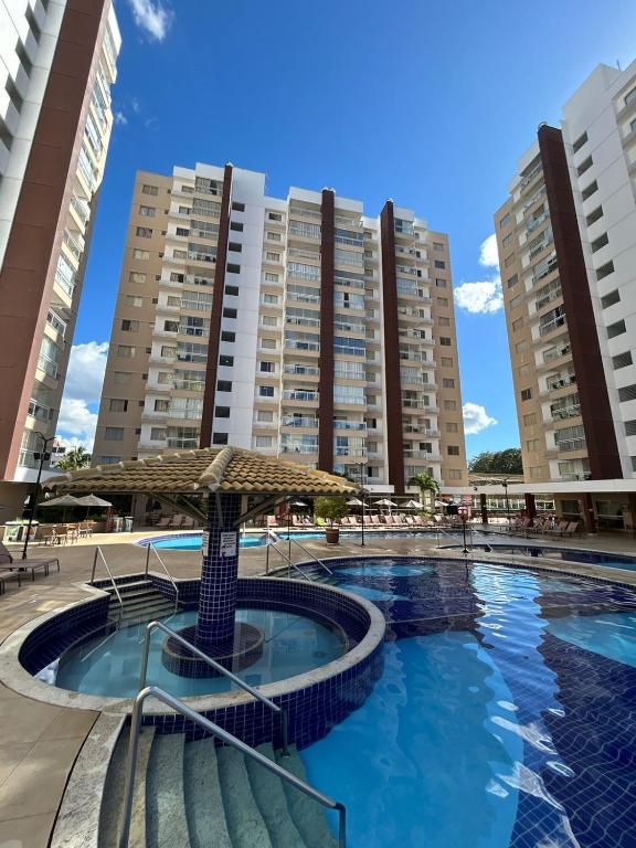a swimming pool with an umbrella and some buildings at Casa da madeira - ate 5 pessoas - Centro in Caldas Novas
