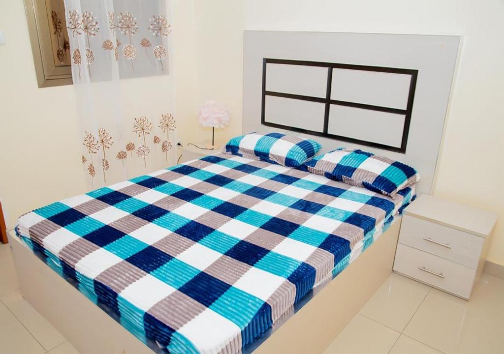 ein Schlafzimmer mit einem blau-weißen karierten Bett in der Unterkunft Voie lactée in Dakar
