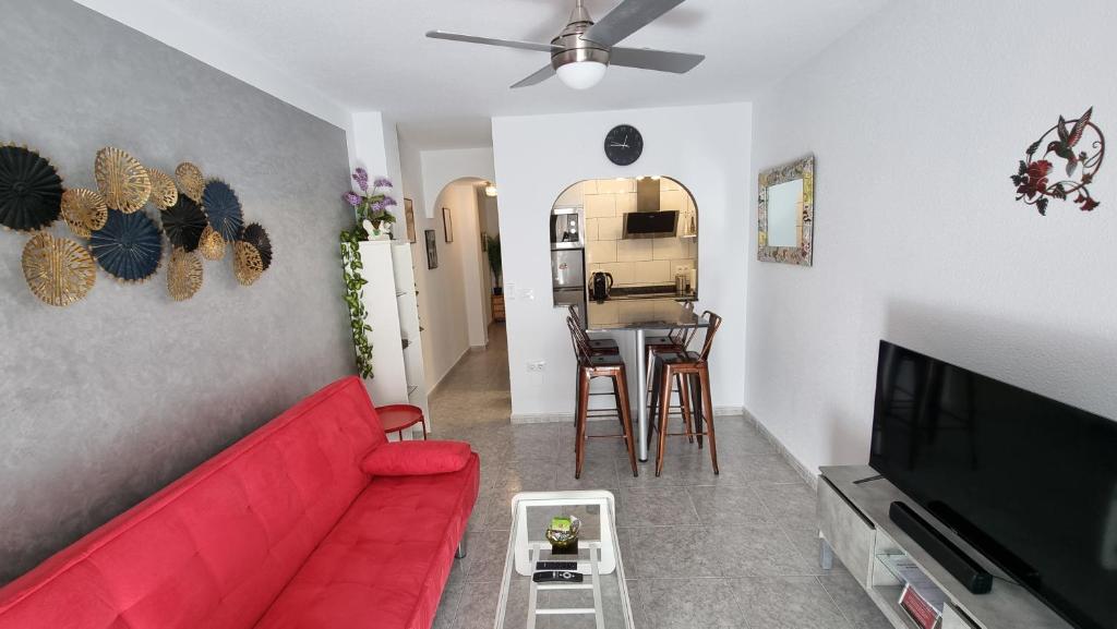 een woonkamer met een rode bank en een tafel bij AYAHAY, Modern luxury apartment just 50 m from Playa Del Puerto in Puerto de Mazarrón