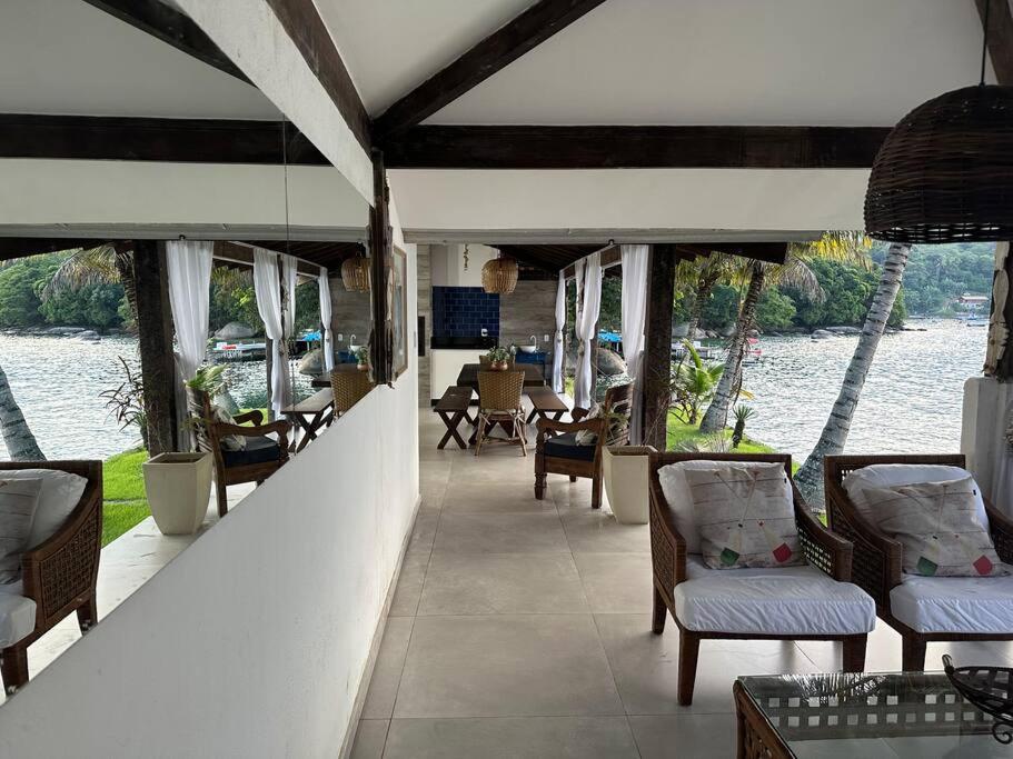 a living room with chairs and a view of the water at Casa de veraneio com deck em Passa Terra, Ilha Grande in Angra dos Reis