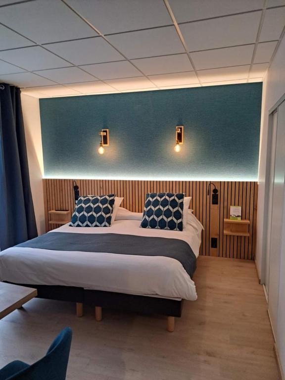 a bedroom with two beds and a blue wall at Hotel Le Lion d'Or in Saint-Geniez-dʼOlt