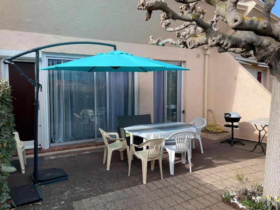 - une table, des chaises et un parasol sur la terrasse dans l'établissement Appartement T2 avec terrasses, à Le Castellas