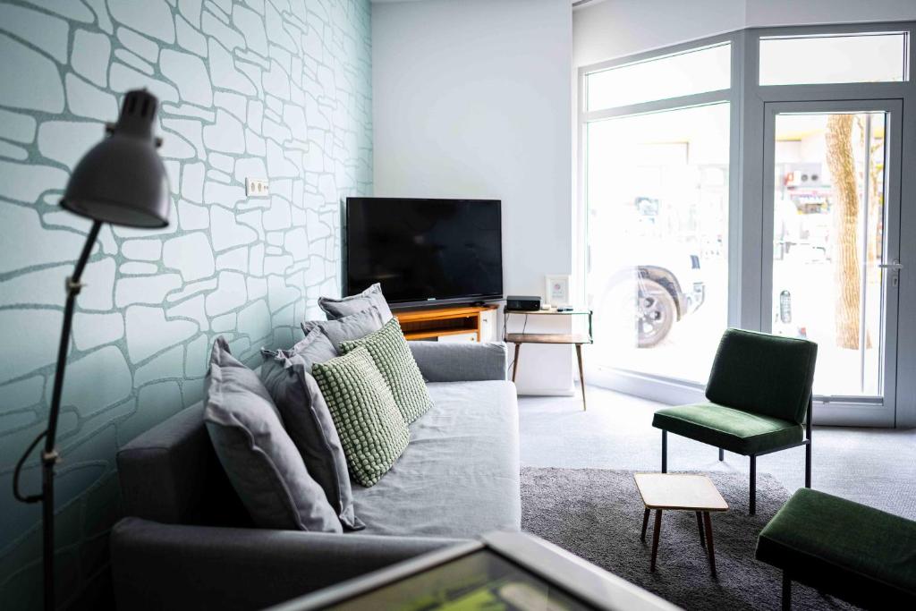 ein Wohnzimmer mit einem Sofa und einem TV in der Unterkunft Das Quartier in Klagenfurt am Wörthersee