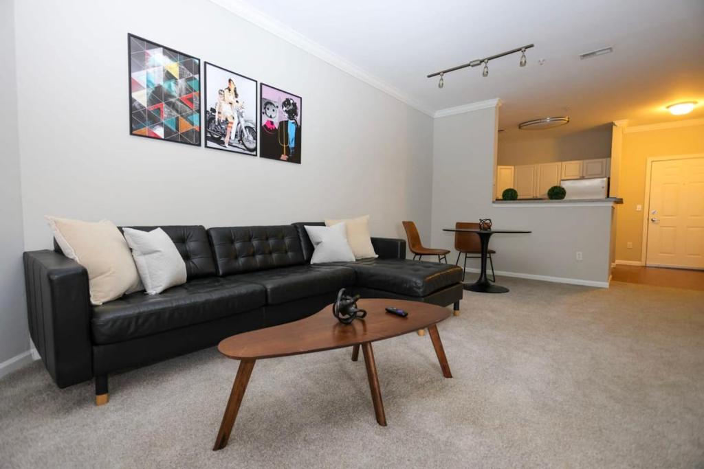 a living room with a black leather couch and a table at Comfortable Apartment with Pool Gym & other Amenities #2306 in Woburn