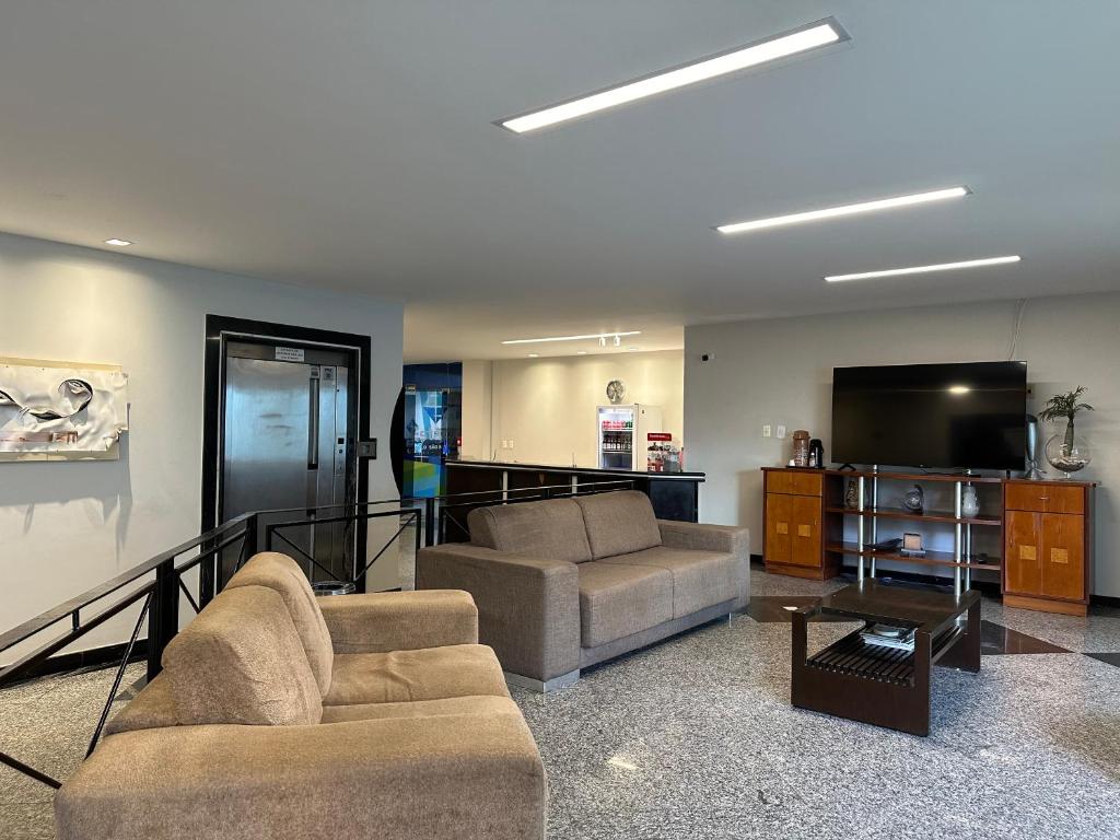 a living room with two couches and a flat screen tv at Norte Palace Hotel in São Mateus