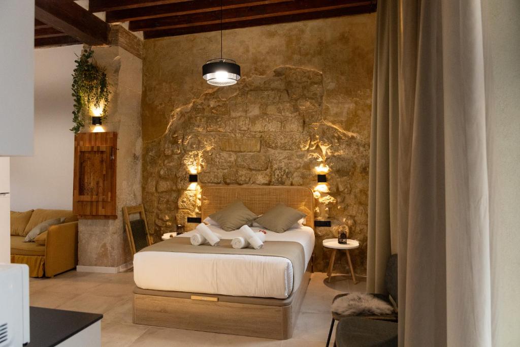 1 dormitorio con 1 cama frente a una pared de piedra en HGB CATHEDRAL, en Alicante
