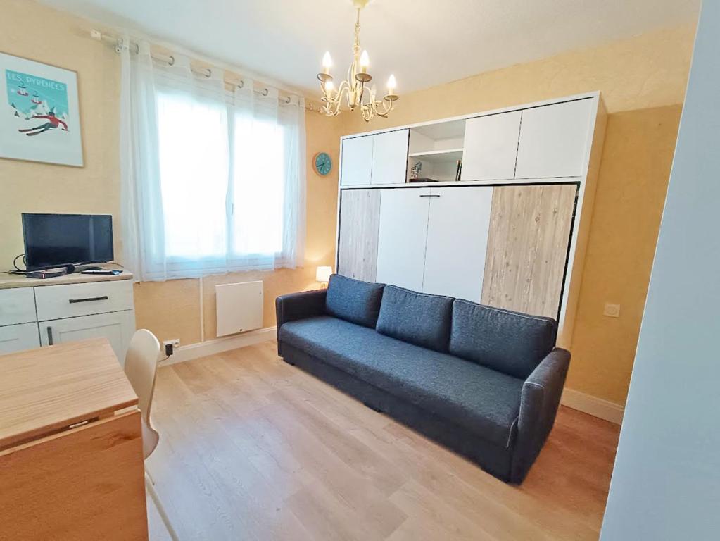 un salon avec un canapé bleu et une télévision dans l'établissement Les Myrtilles, studio, wifi, cave, 2 personnes, à Luchon