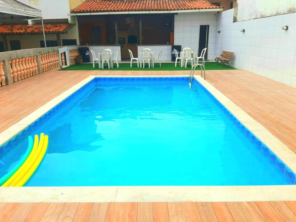 a large swimming pool with a wooden deck and chairs at Flamboyant hostel in Cabo Frio
