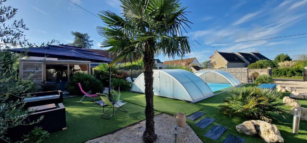 un patio con una tienda y una palmera en Gite La Belle Aventure Mosnes piscine jacuzzi capacité 15 PERS en Mosnes