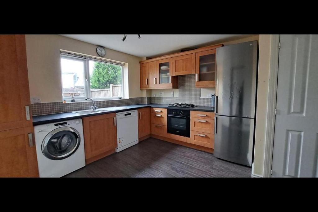a kitchen with a refrigerator and a washer and dryer at Budget rooms in Dudley in Tipton